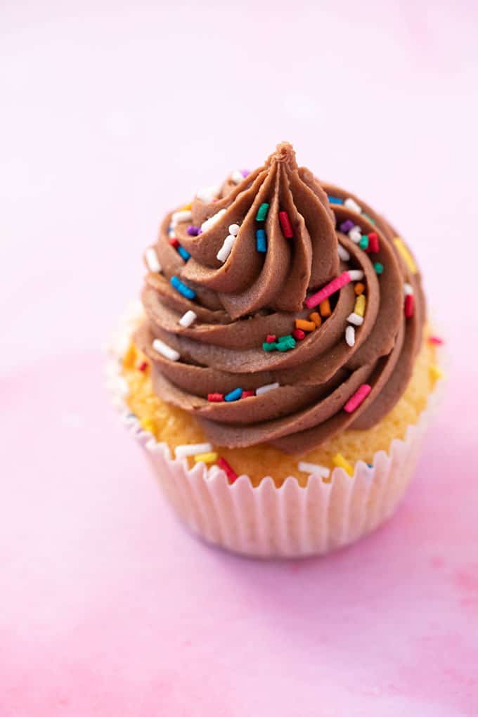 Close up of a cupcake topped with chocolate frosting and sprinkles