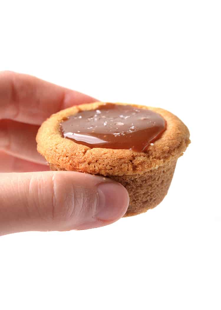 Hand holding a cookie cup filled with caramel sauce