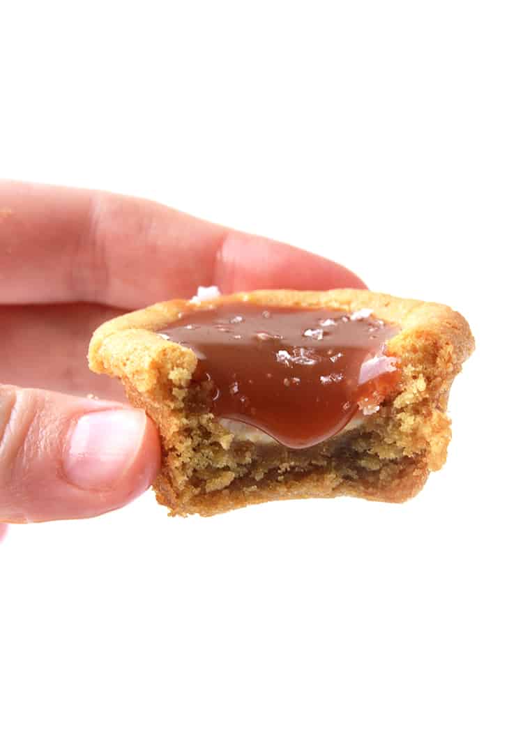 A hand holding a cookie cup filled with caramel sauce 