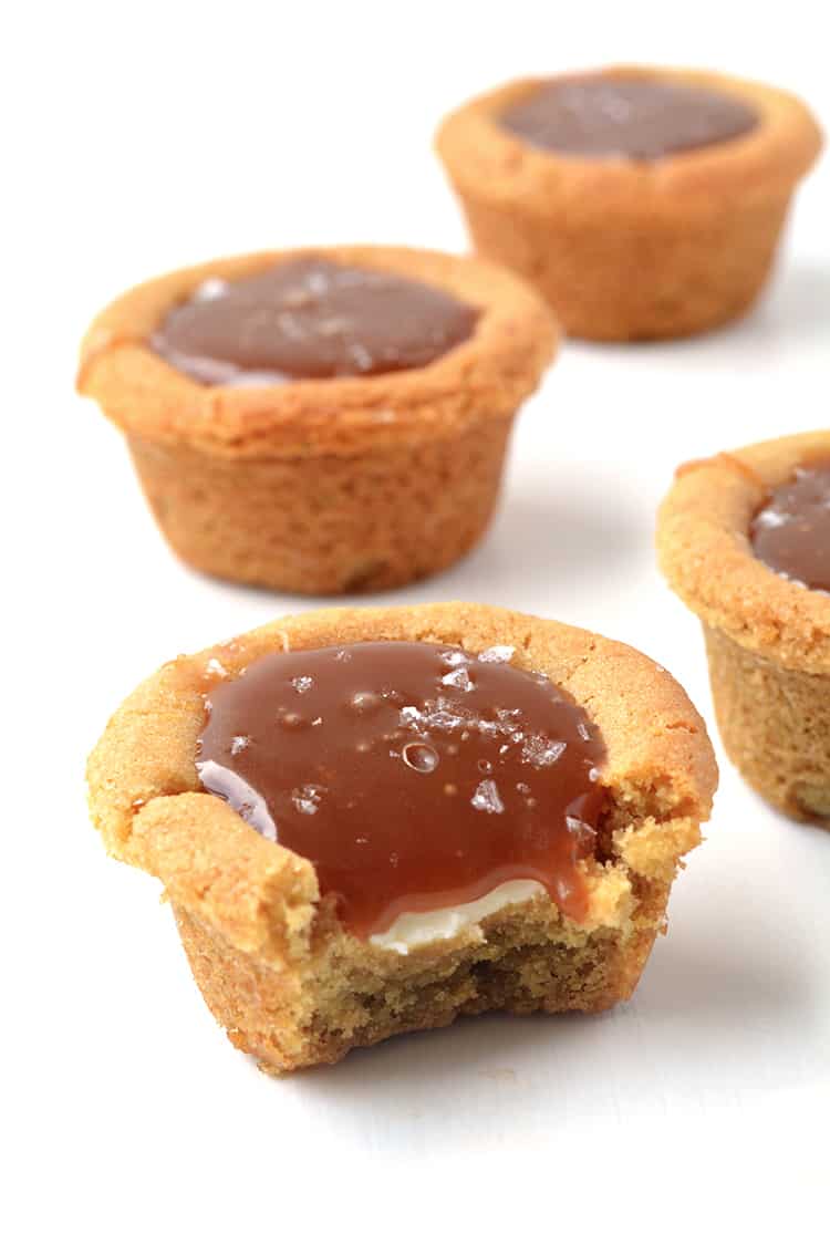 Cookie cups filled with caramel sauce with a bite taken out of it