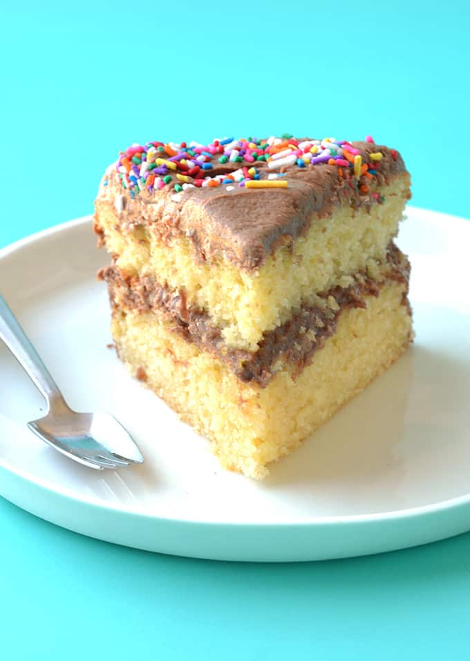 A slice of yellow cake with Nutella frosting on a white plate