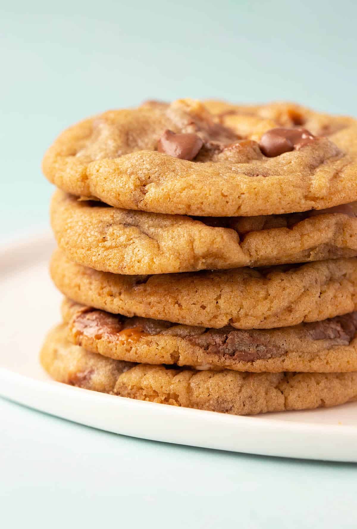 A stack of crispy Snickers Cookies on a white plate.