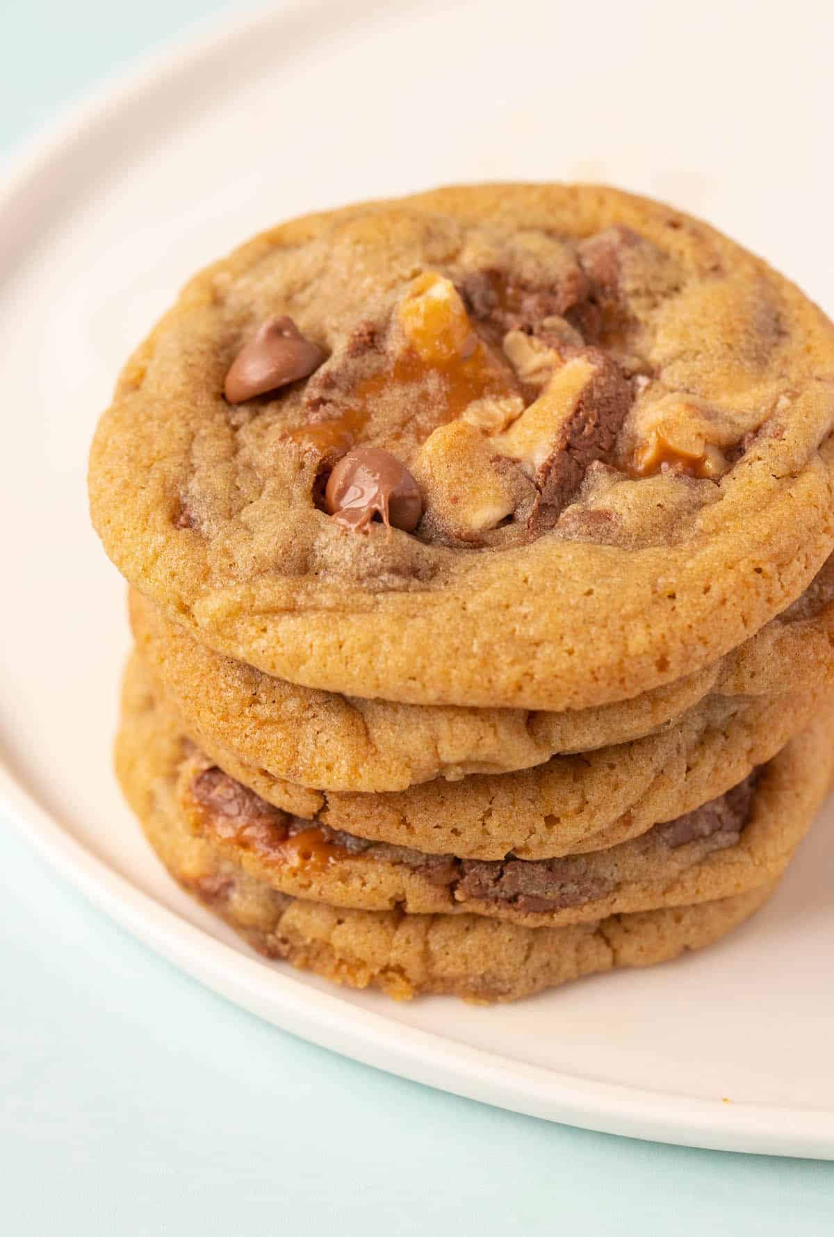 A stack of thin and crispy Snickers Cookies on a white plate. 