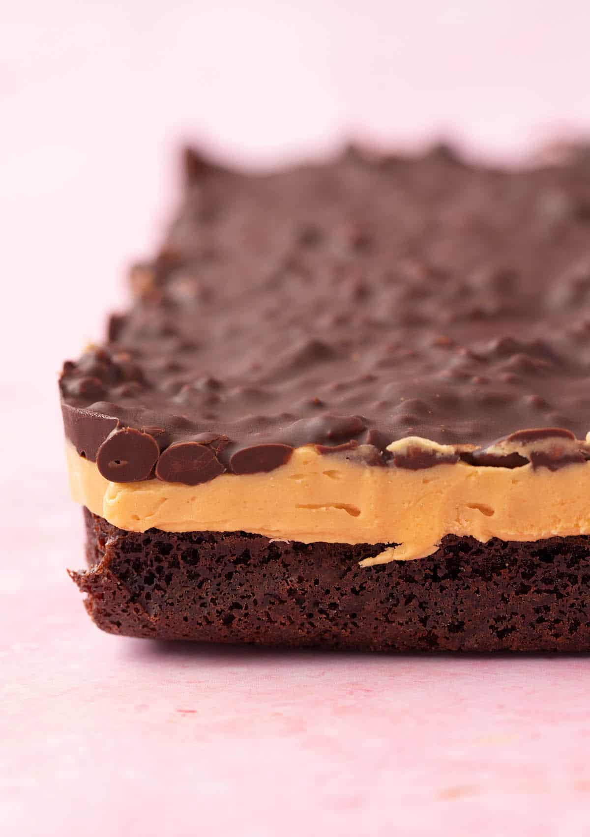 A slab of homemade Peanut Butter Brownies sitting on a pink background.