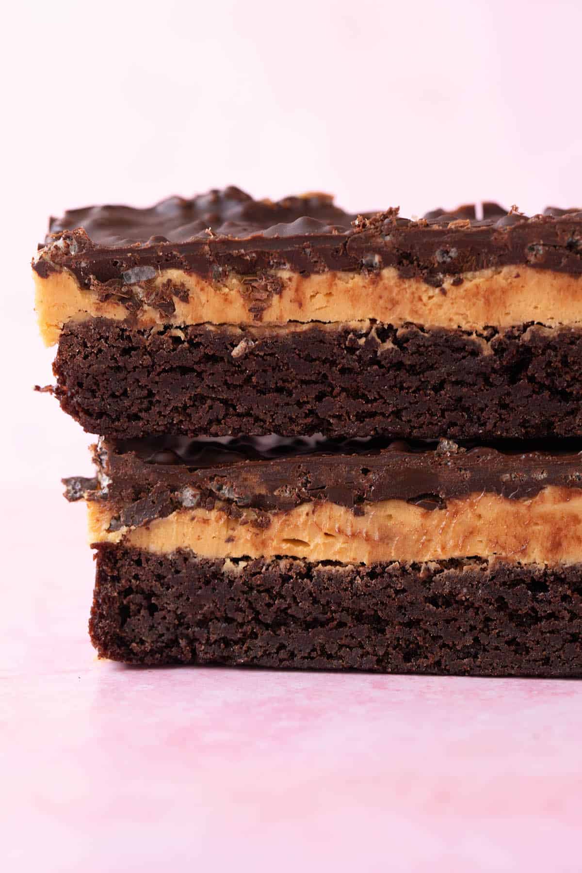 Close up showing three amazing layers of brownie on a pink background.