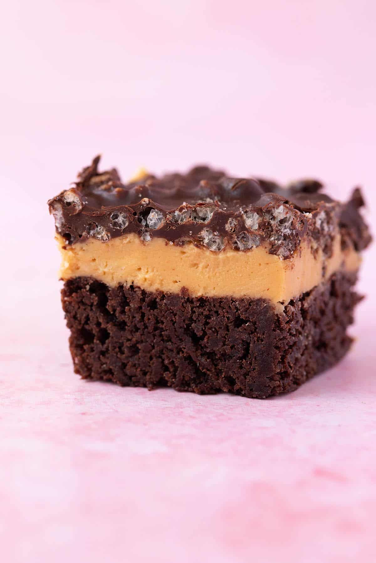 Close up of one slice of Peanut Butter Brownie Bars on a pink background.