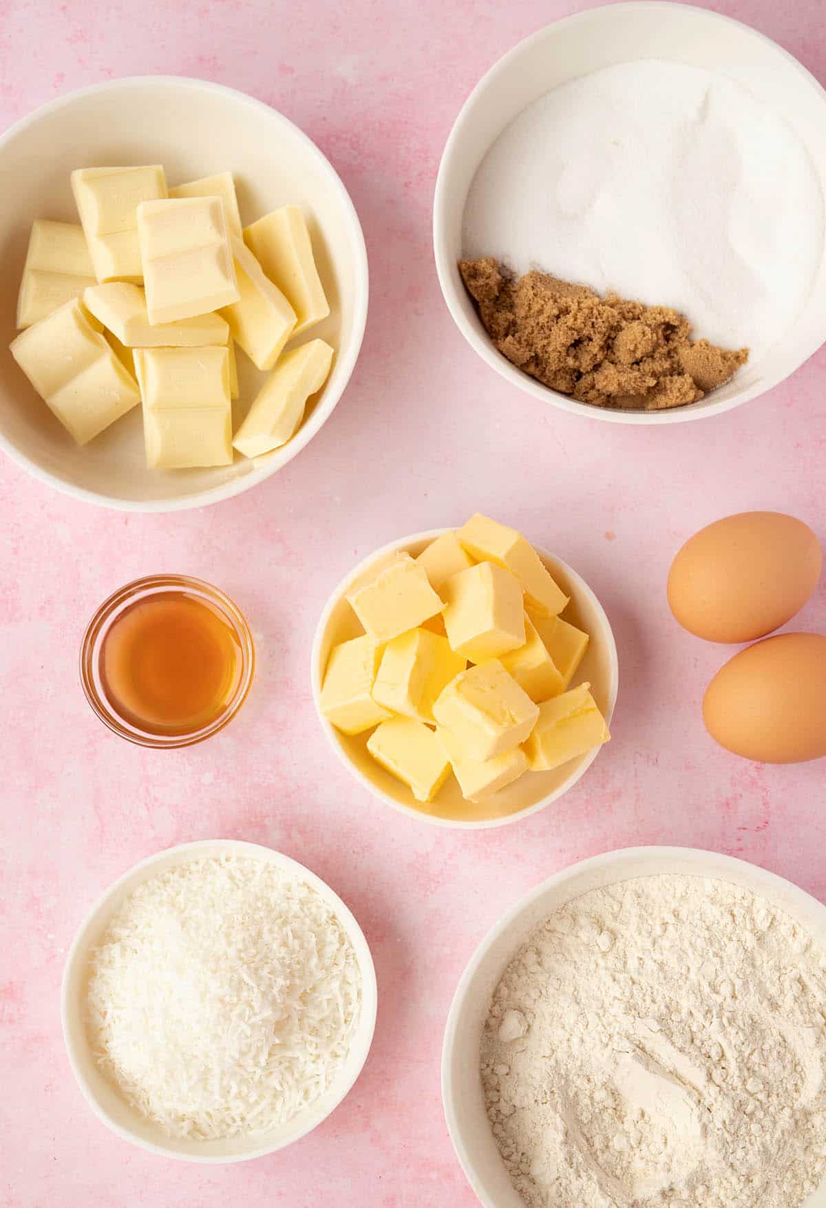 All the ingredients needed to make White Chocolate Coconut Brownies on a pink background.
