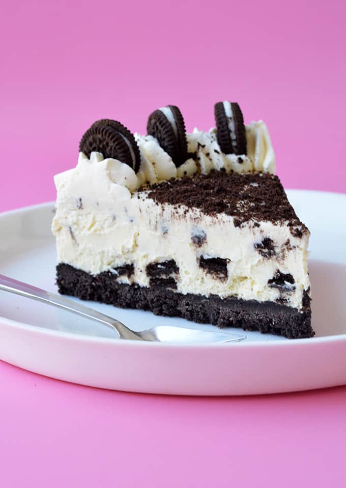 A slice of Oreo Cheesecake on a pink background