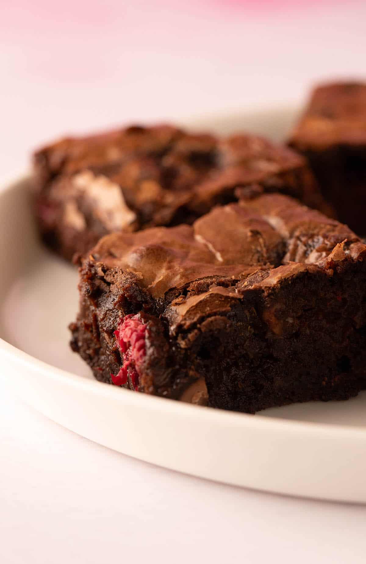 A gooey chocolate brownies on a pink background.