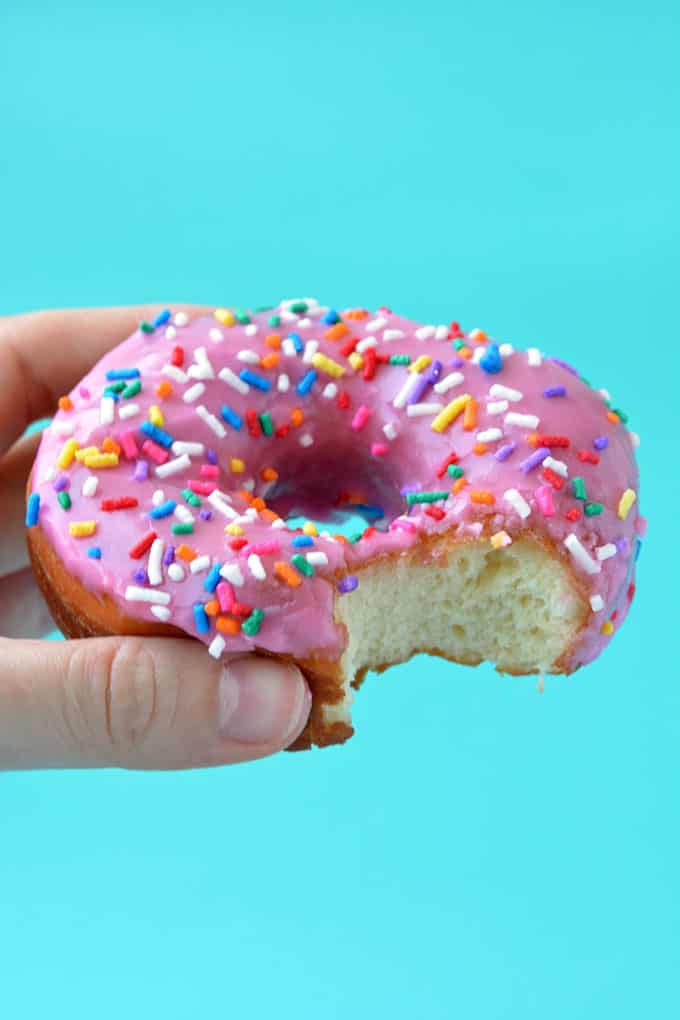 A hand holding a Homer Simpson Donut with a bite taken out of it