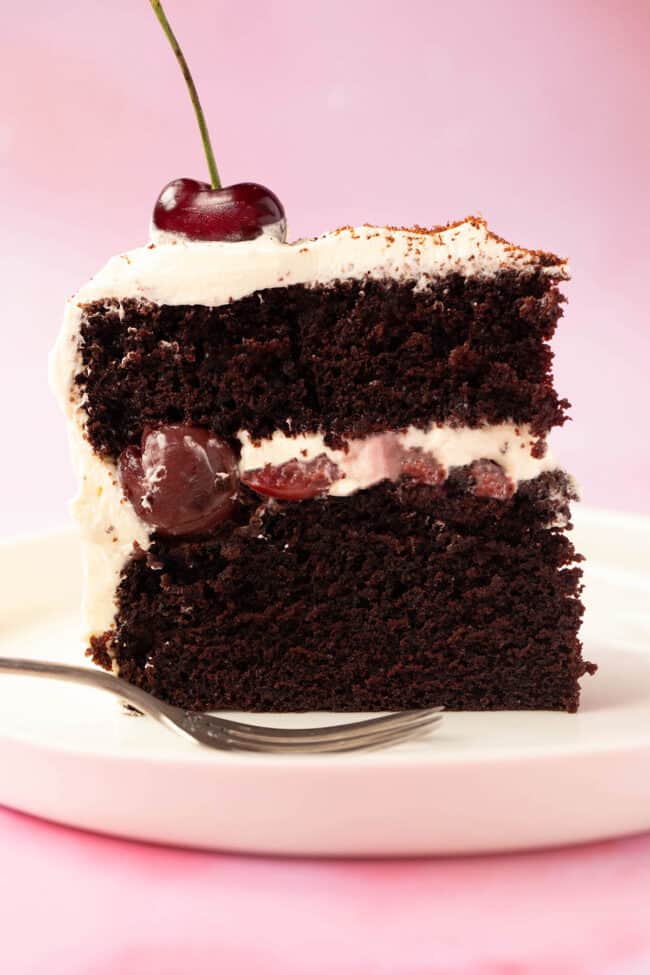 A beautiful slice of homemade black forest cake on a pink backdrop.