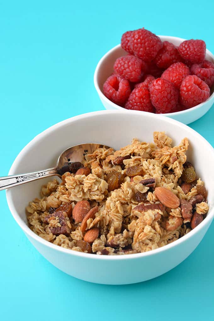 A bowl of homemade granola with fresh berries on the side