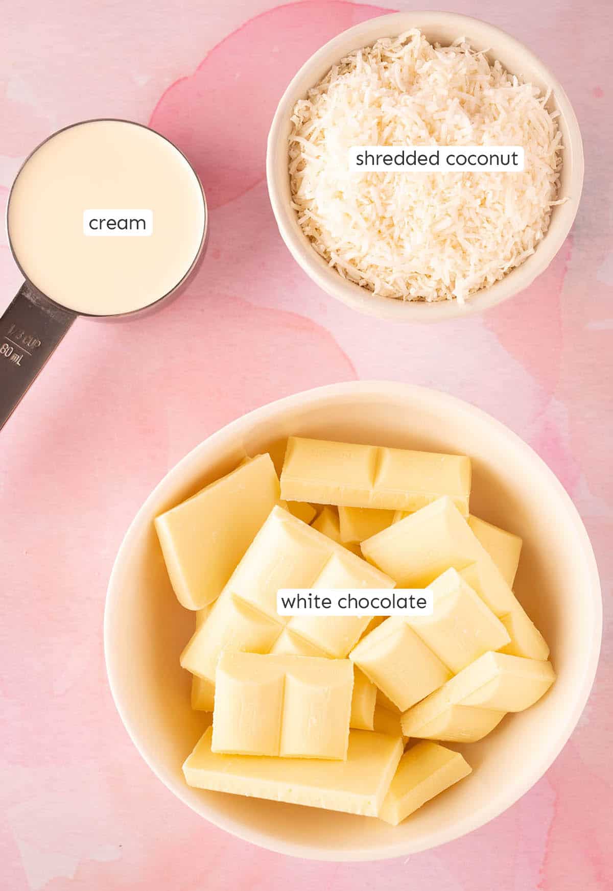 All the ingredients needed to make white chocolate truffles at home on a pink background.