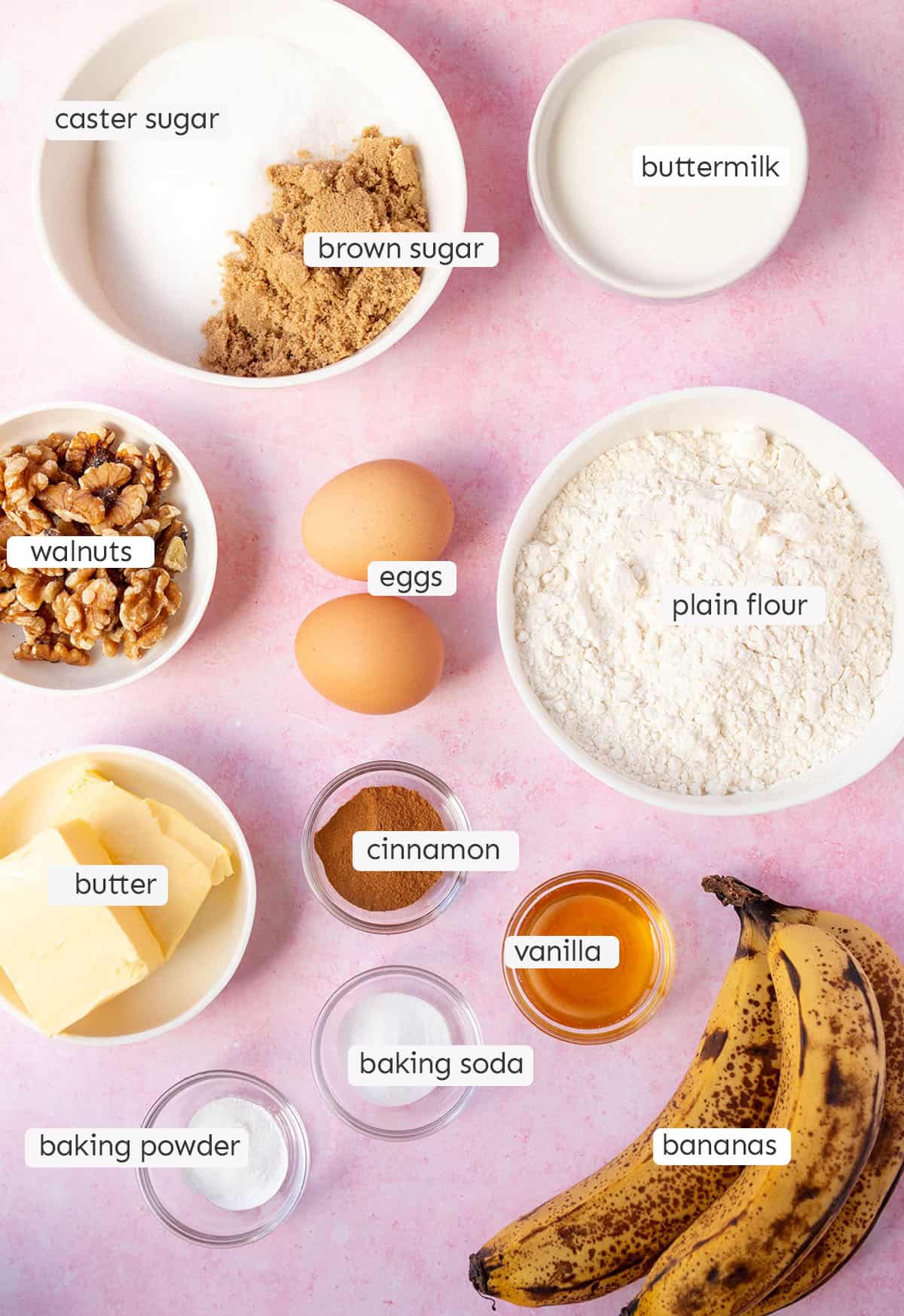 All the ingredients needed to make Banana Cake from scratch on a pink background. 