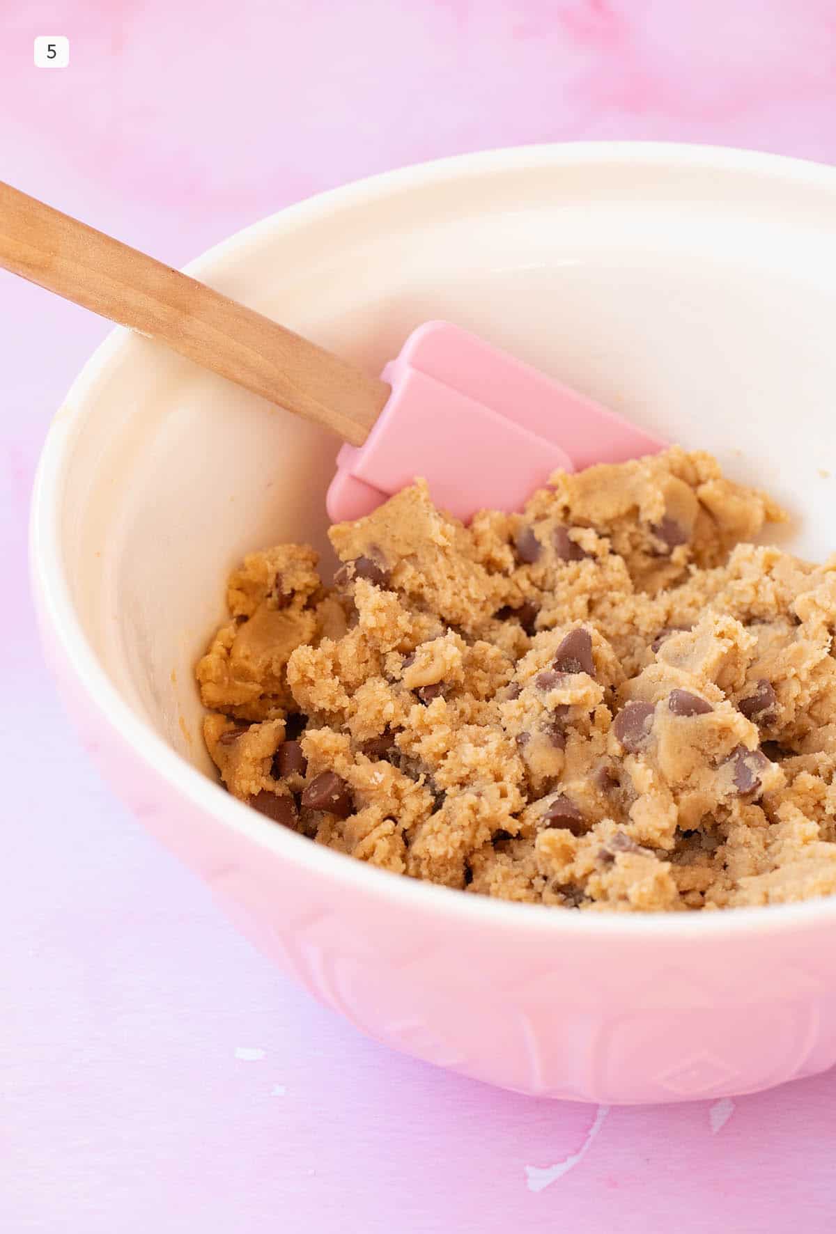 A pink bowl filled with chocolate chip cookie dough.