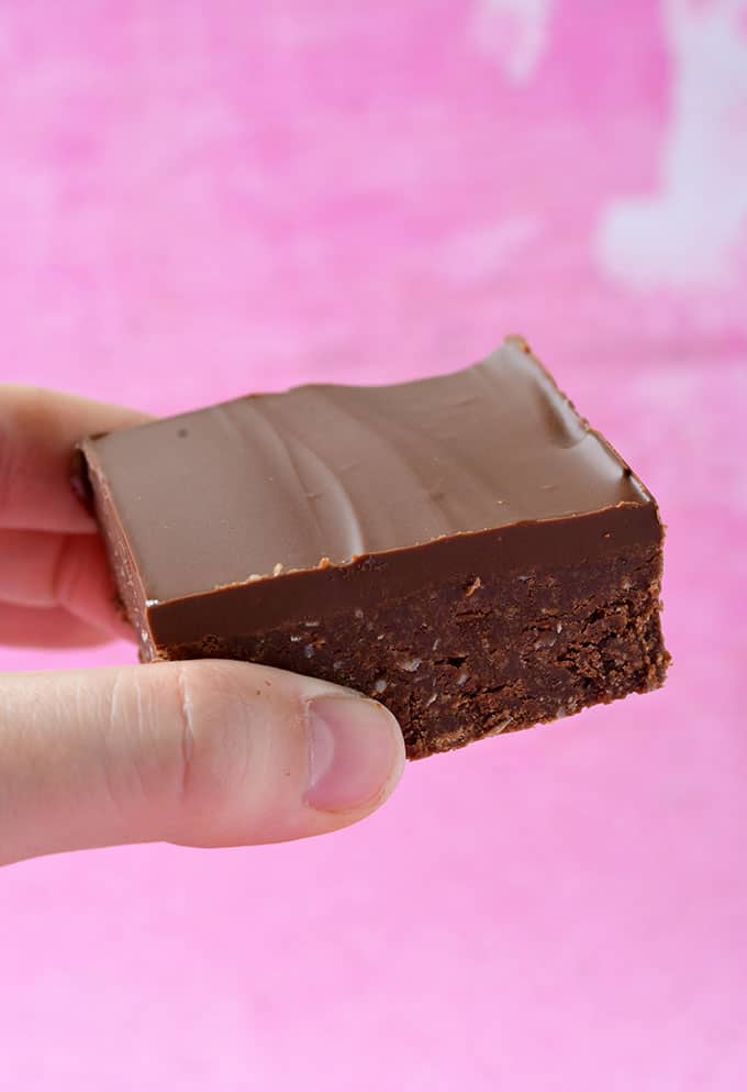 A hand holding a piece of Chocolate Slice