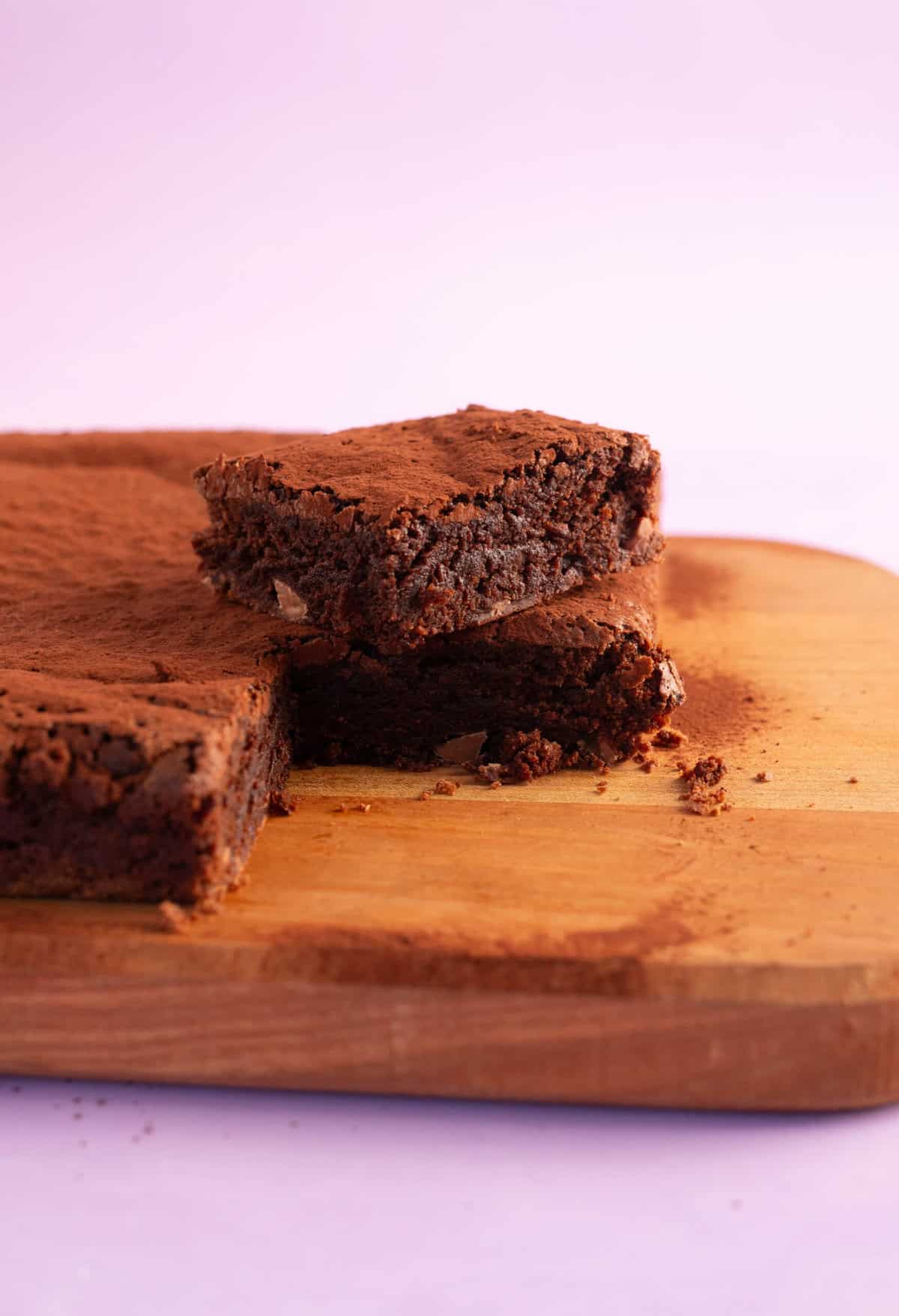Slice of brownie sitting on a wooden cutting board.
