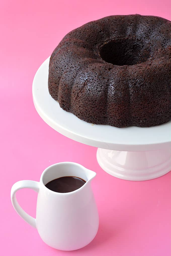 A Chocolate Bundt Cake with a pot of chocolate ganache sitting next to it