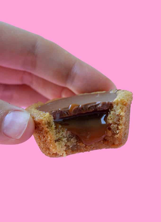 A hand holding a Twix Cookie Cup with a bite taken out of it