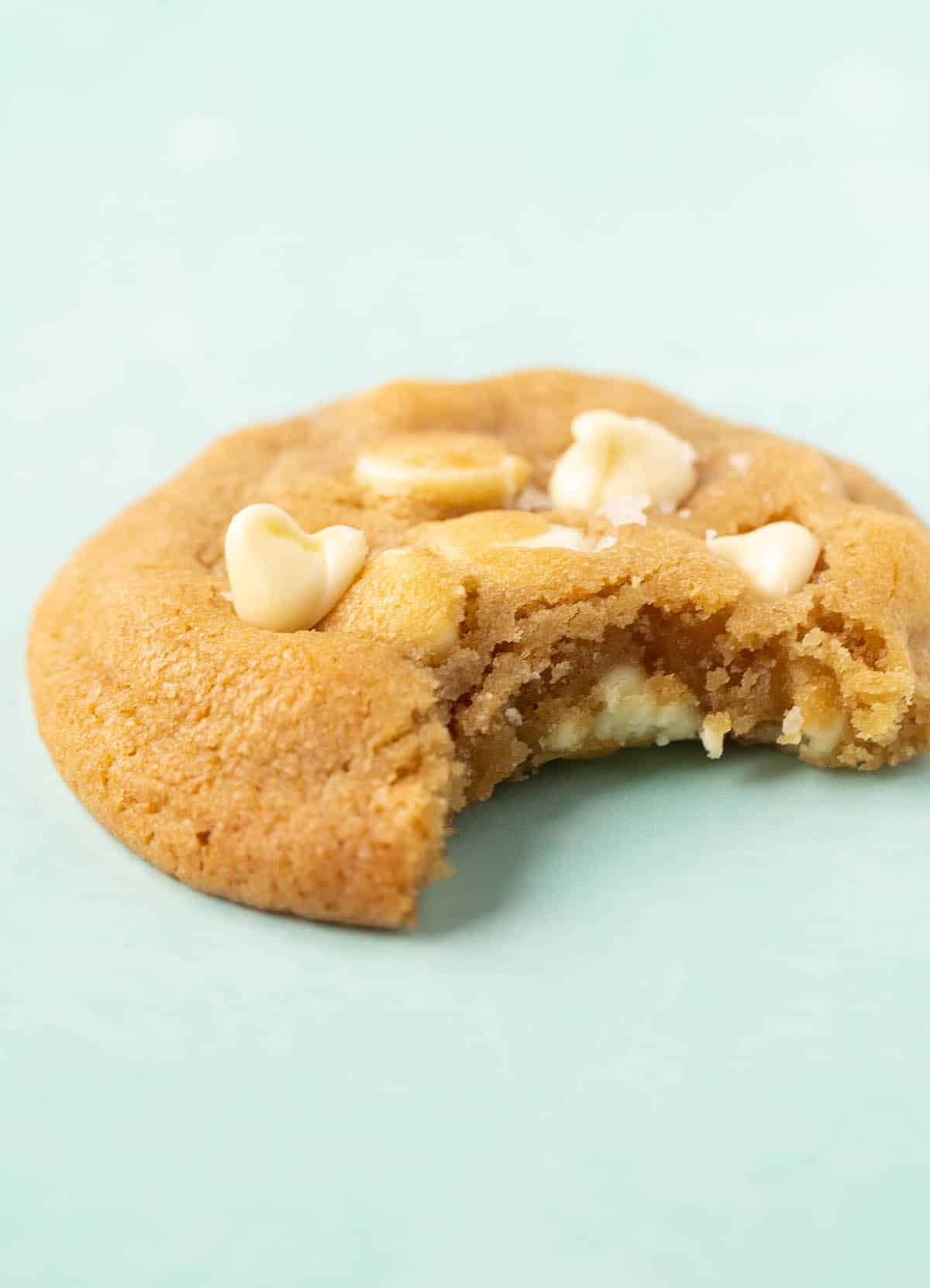 A chewy White Chocolate Chip Cookie with a bite taken out of it. 