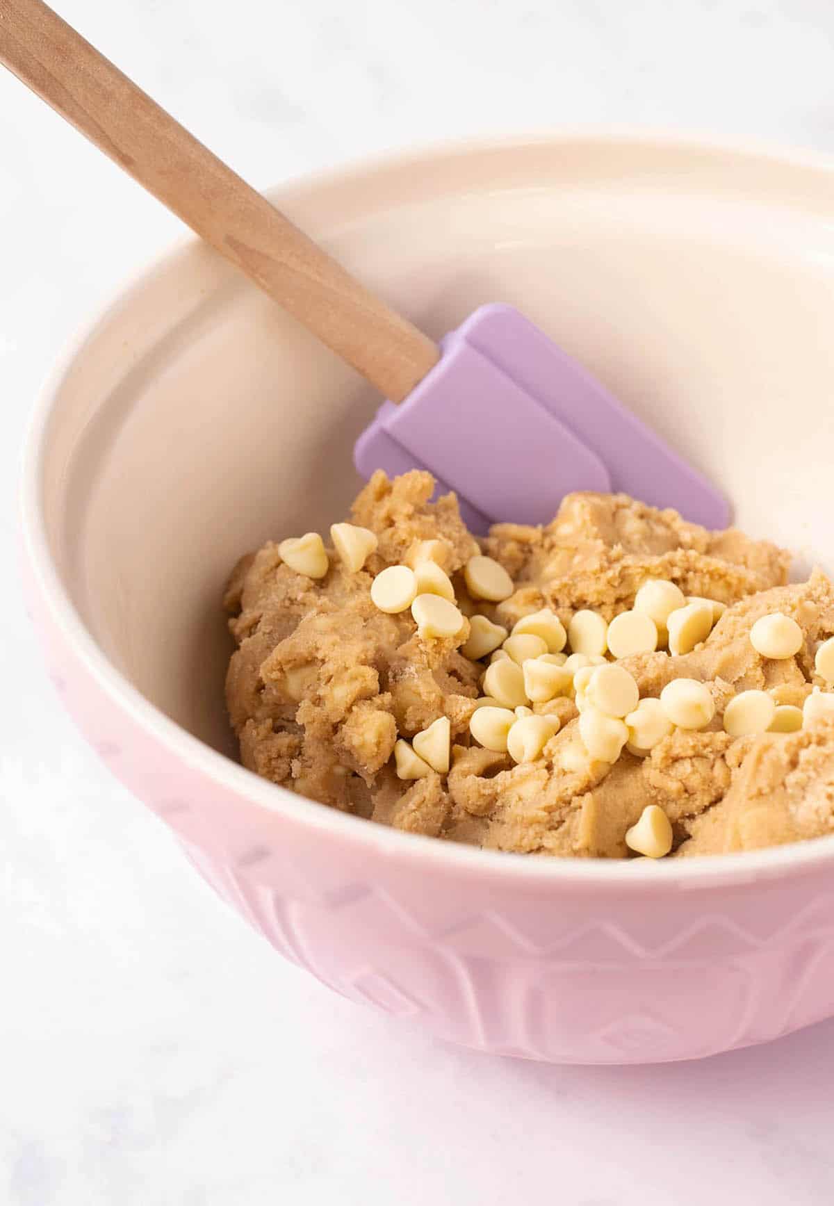 A pink mixing bowl full of homemade cookie dough. 