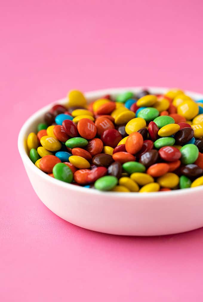 A bowl of mimi M&M's on a pink background