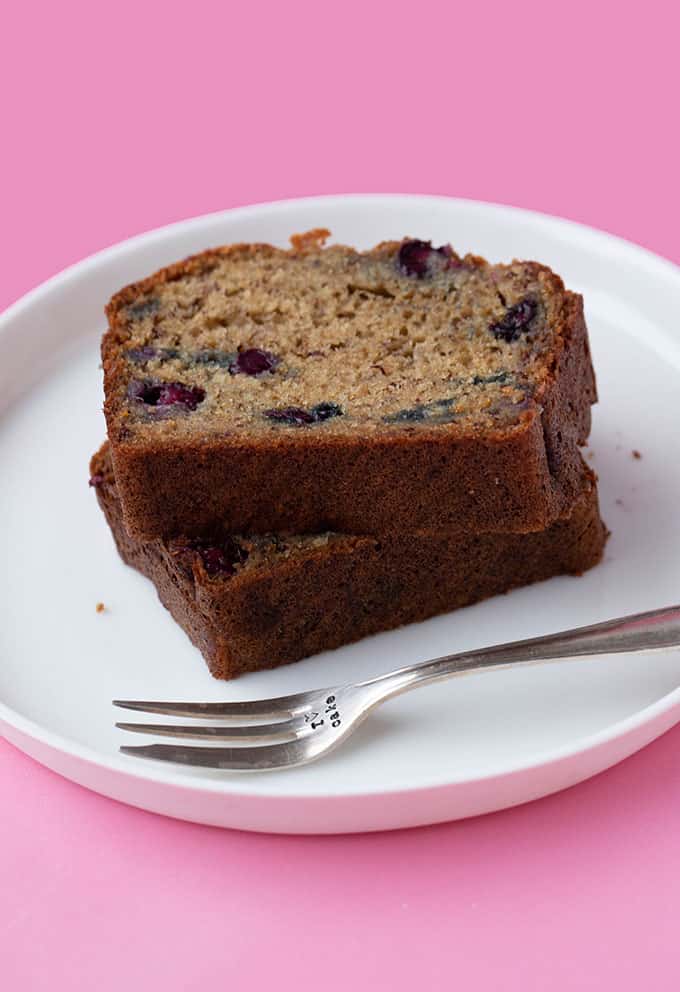 A slice of banana bread on a white plate with a fork