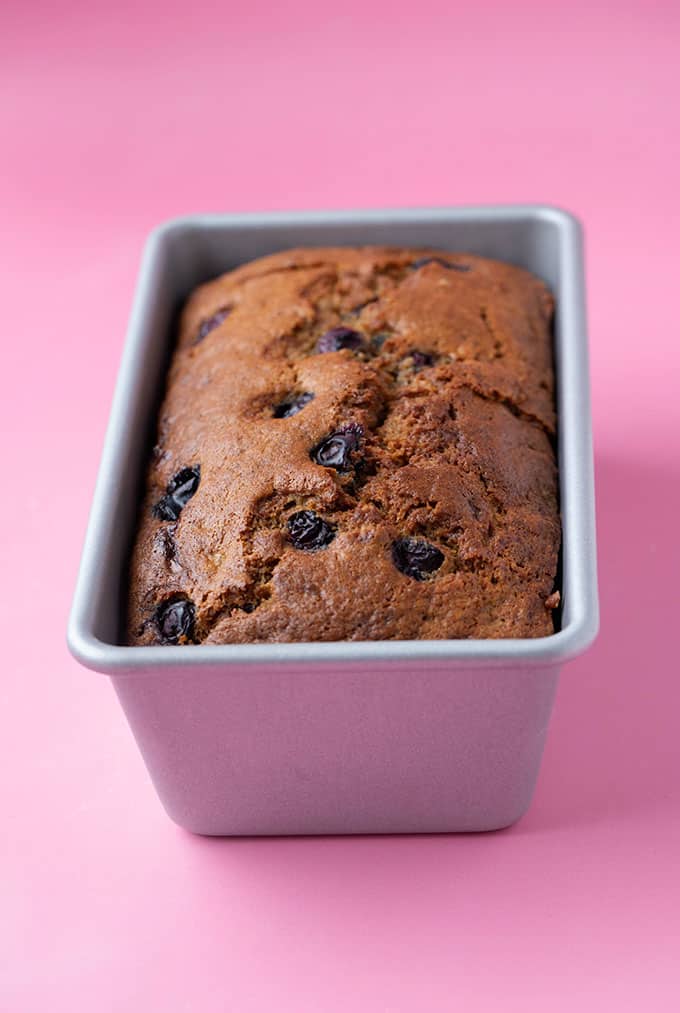 A loaf od Blueberry Banana Bread on a pink background