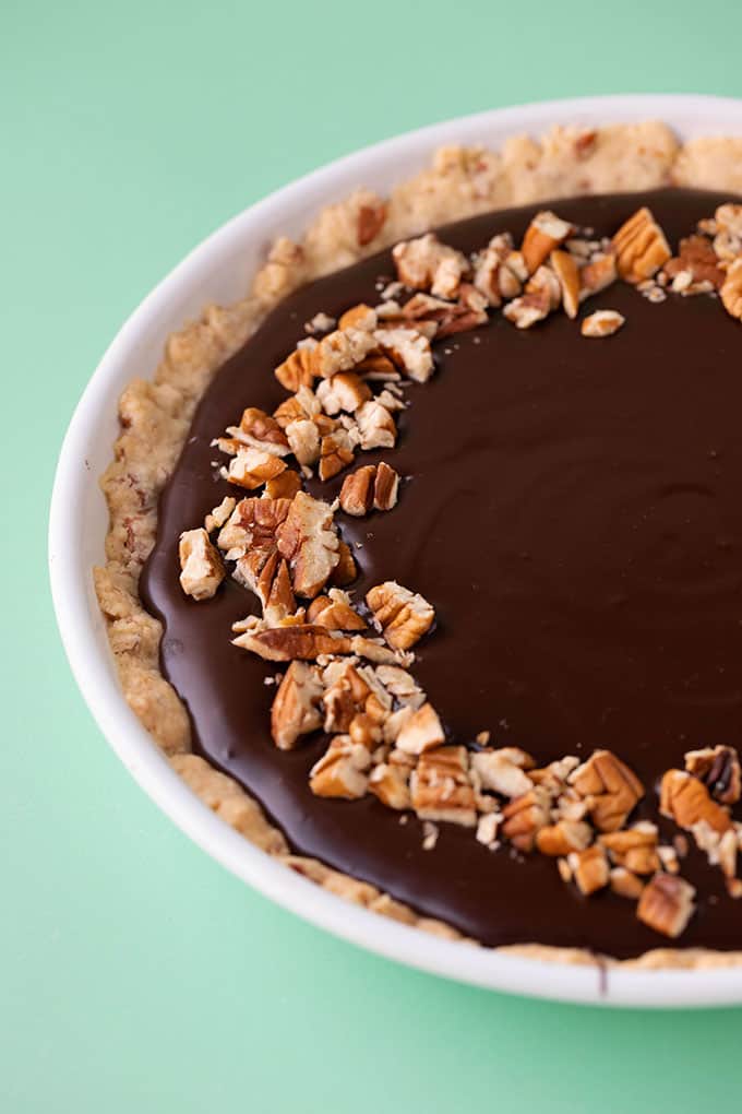 A homemade pie topped with chocolate and pecans