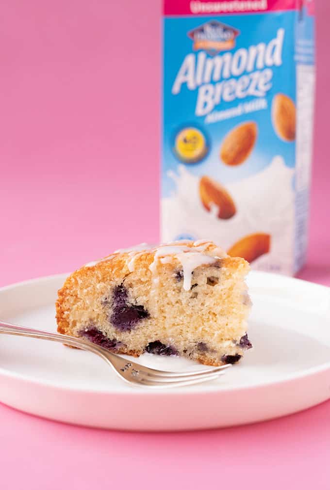 A piece of Blueberry Cake with a bottle of Almond Milk behind it