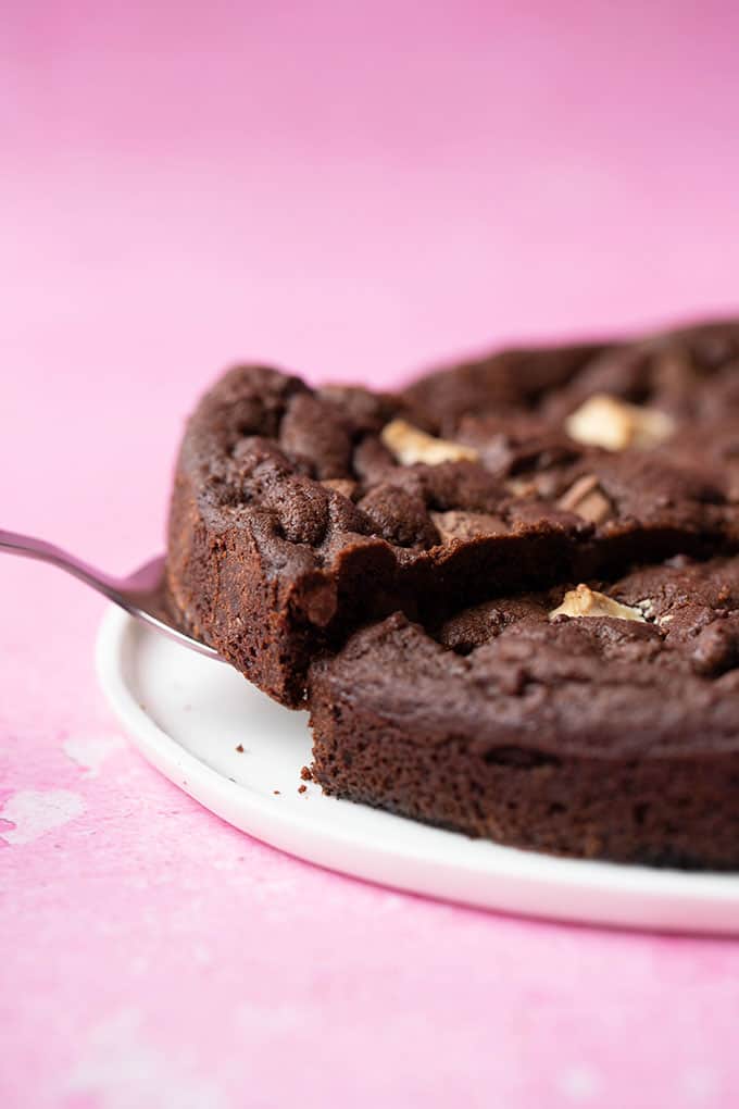 A cake spatula lifting out a slice of Triple Chocolate Cookie Cake