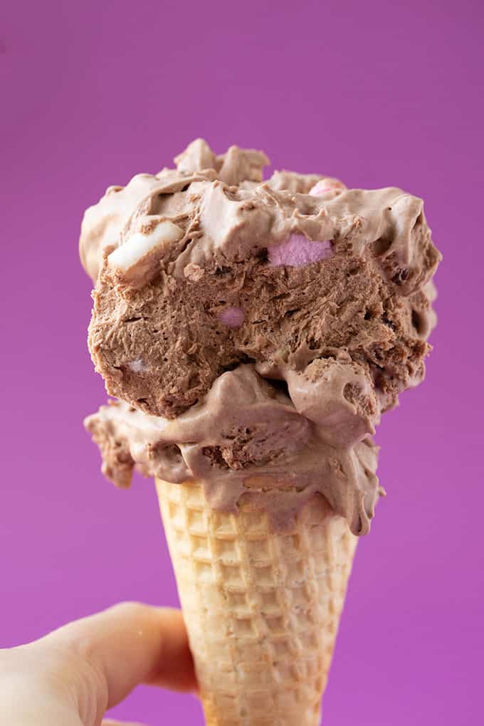 A hand holding a rocky road ice cream cone