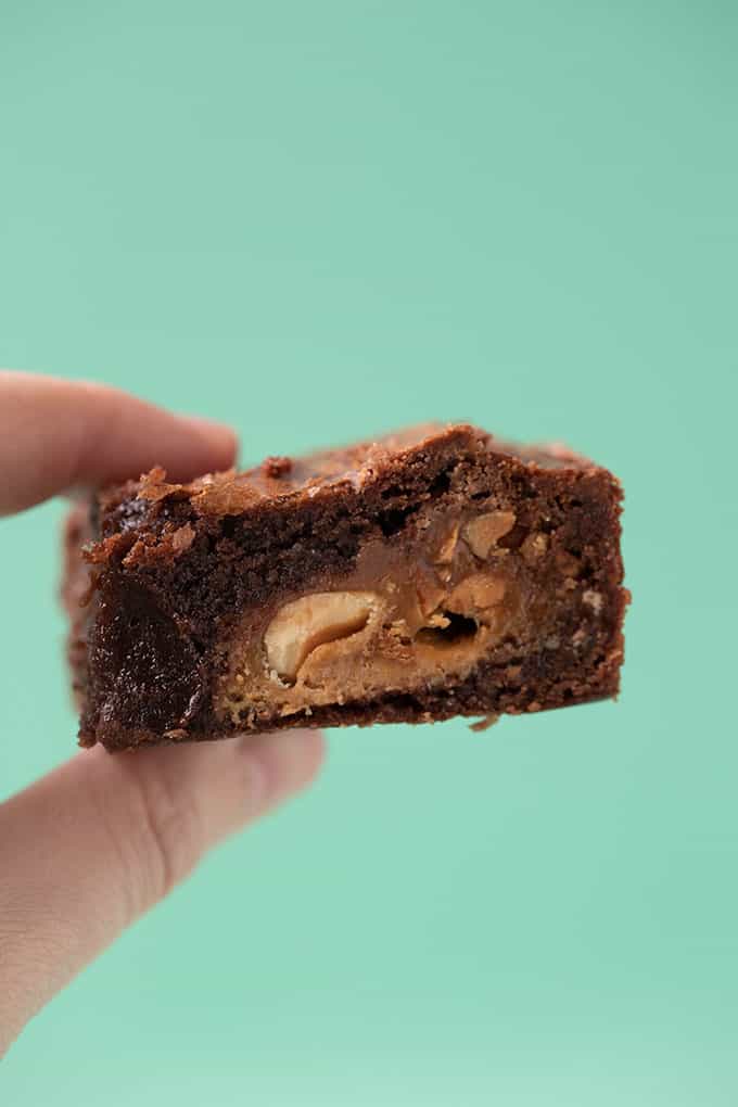 A hand holding a Snickers stuffed chocolate brownie