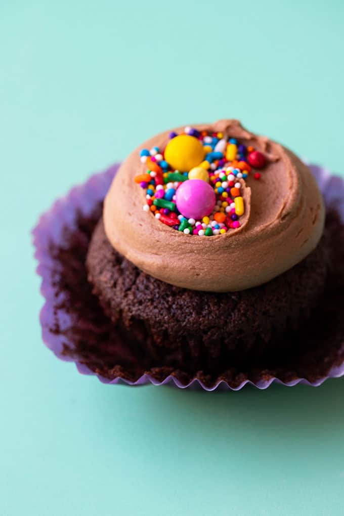 Close up of a chocolate cupcake covered in colourful sprinkles