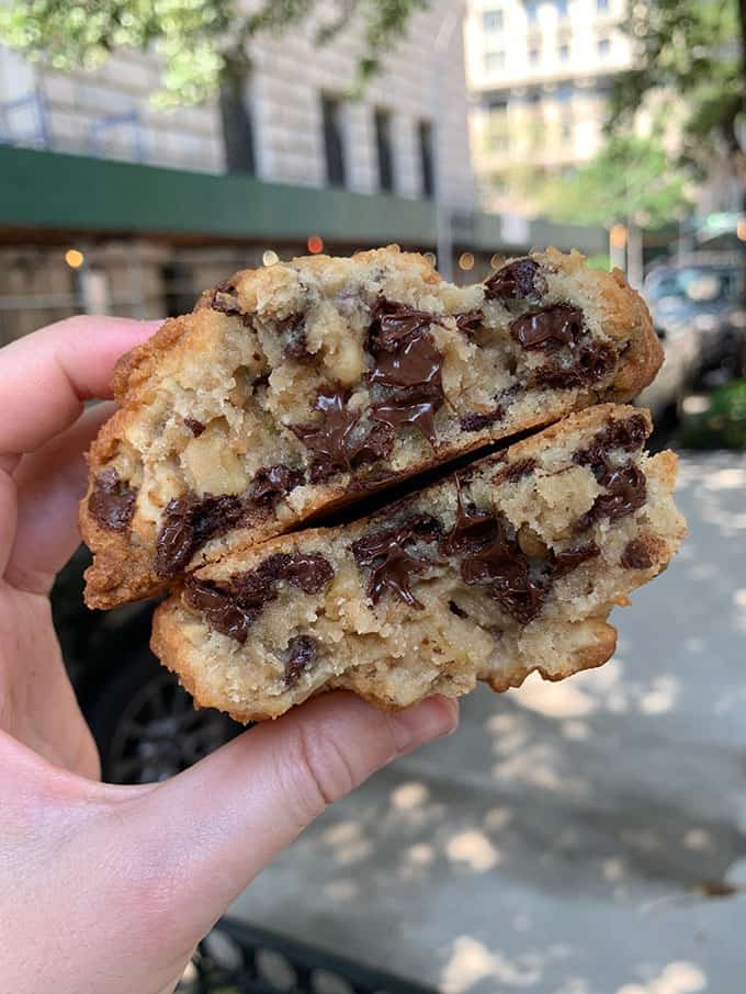A hand holding a chocolate chip cookie from Levain Bakery