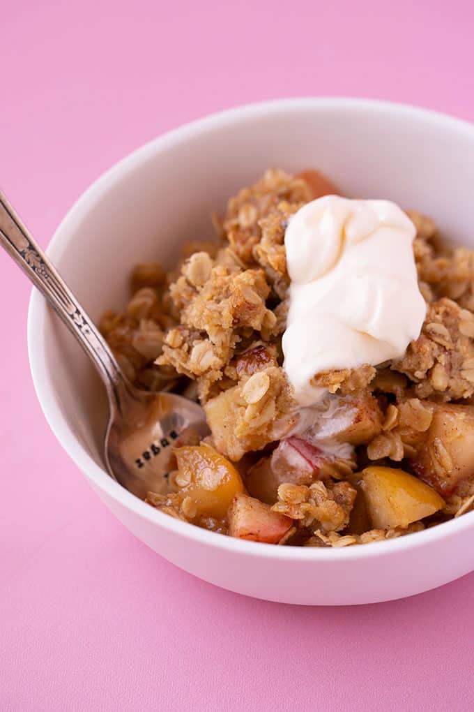A big bowl of apple crumble with whipped cream
