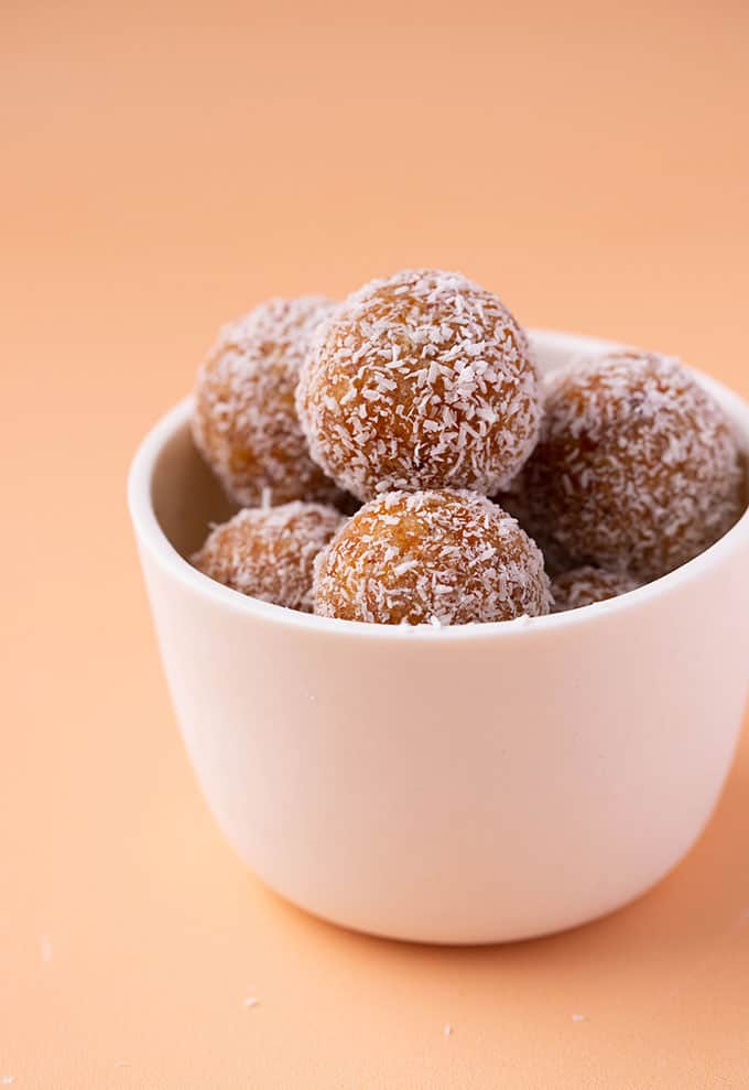 A white bowl filled with Apricot Balls rolled in coconut