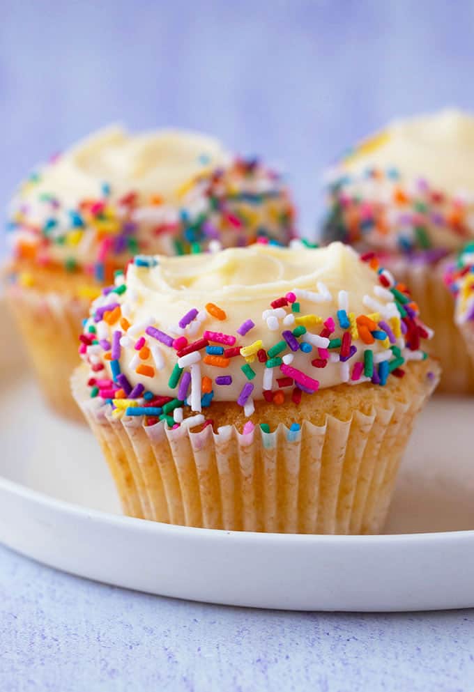 A plate of Vanilla Cupcakes topped with sprinkles