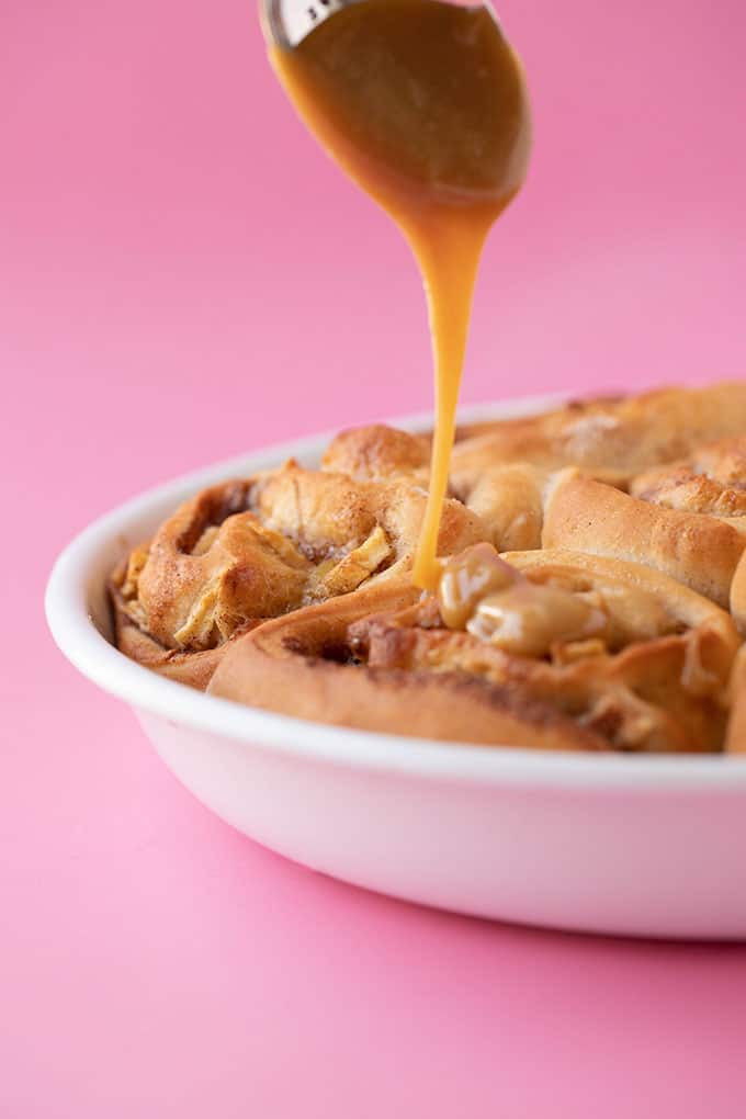 A spoon of caramel drizzled over homemade Cinnamon Apple Buns