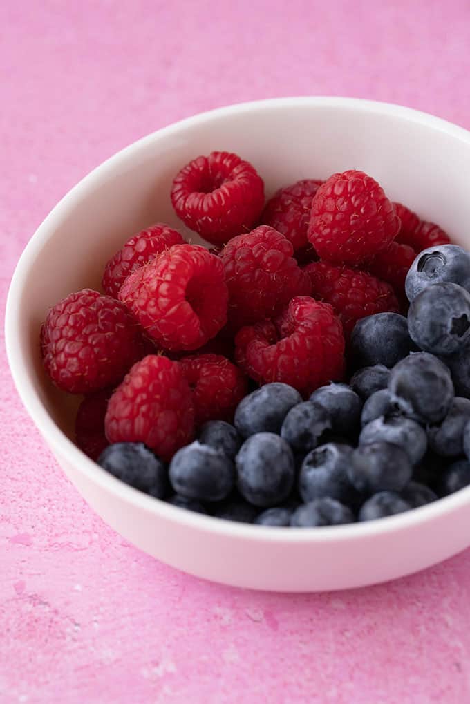 A white bowl filled with raspberries and blueberries