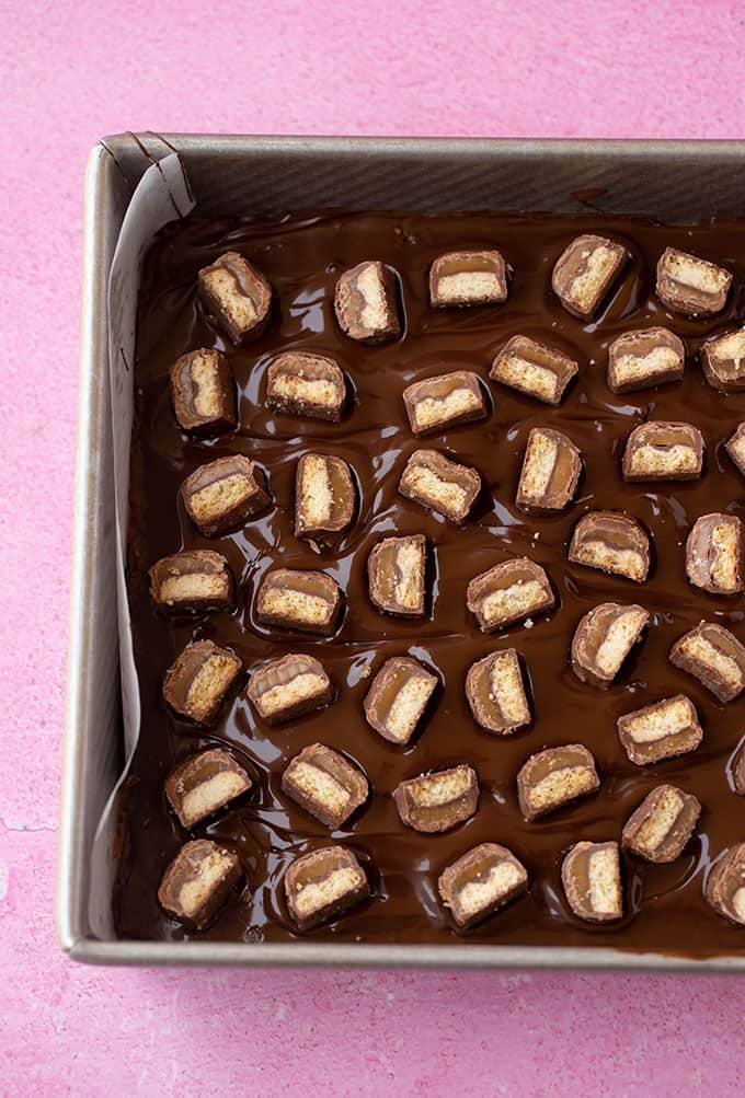 Top view of a chocolate slice covered in chopped Twix Bars