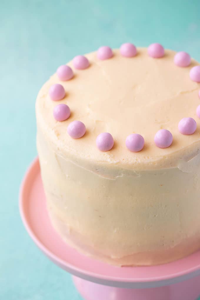 A tall Vanilla Cake on a pink cake stand