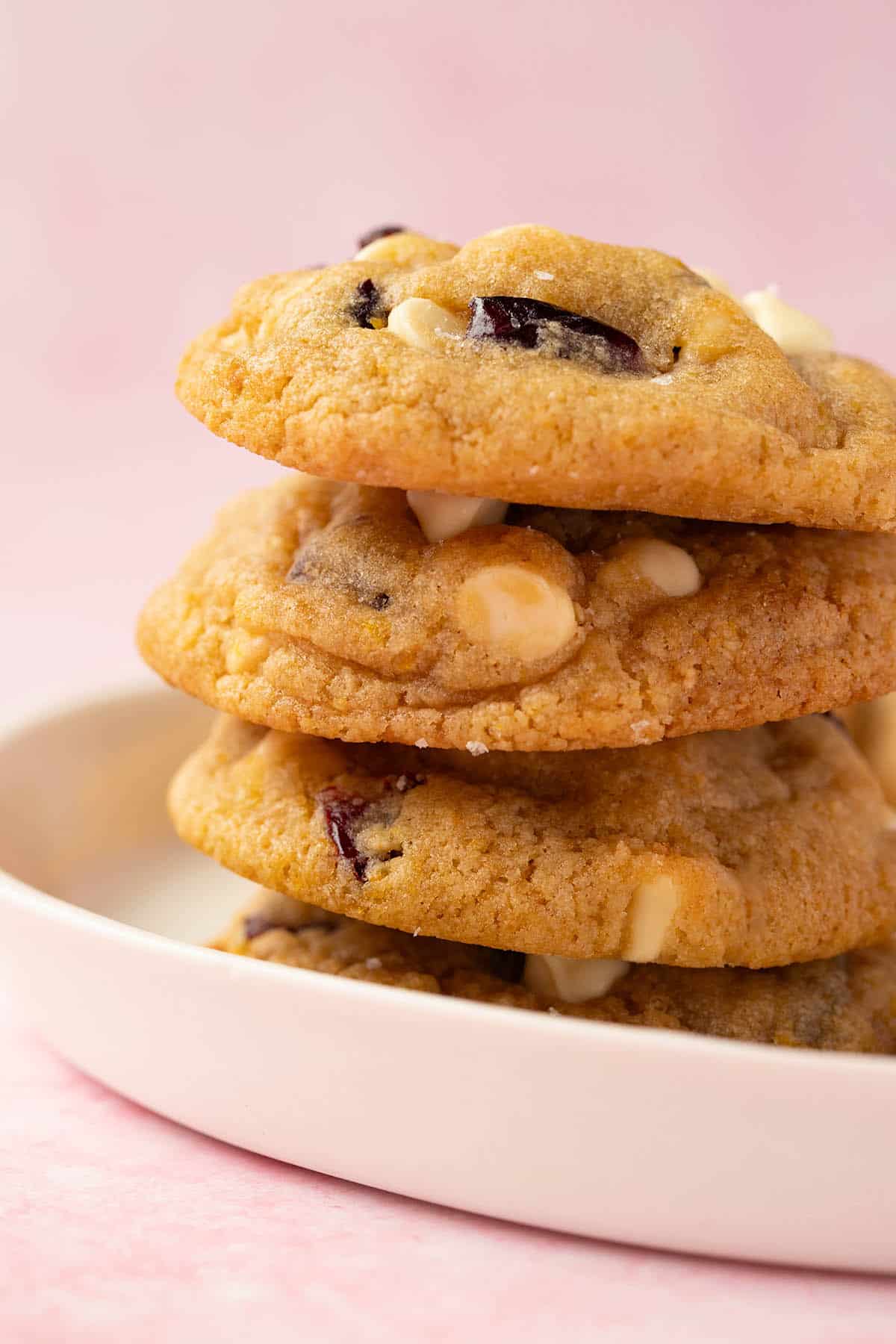 A tall stack of White Chocolate Cranberry Cookies on a white plate. 