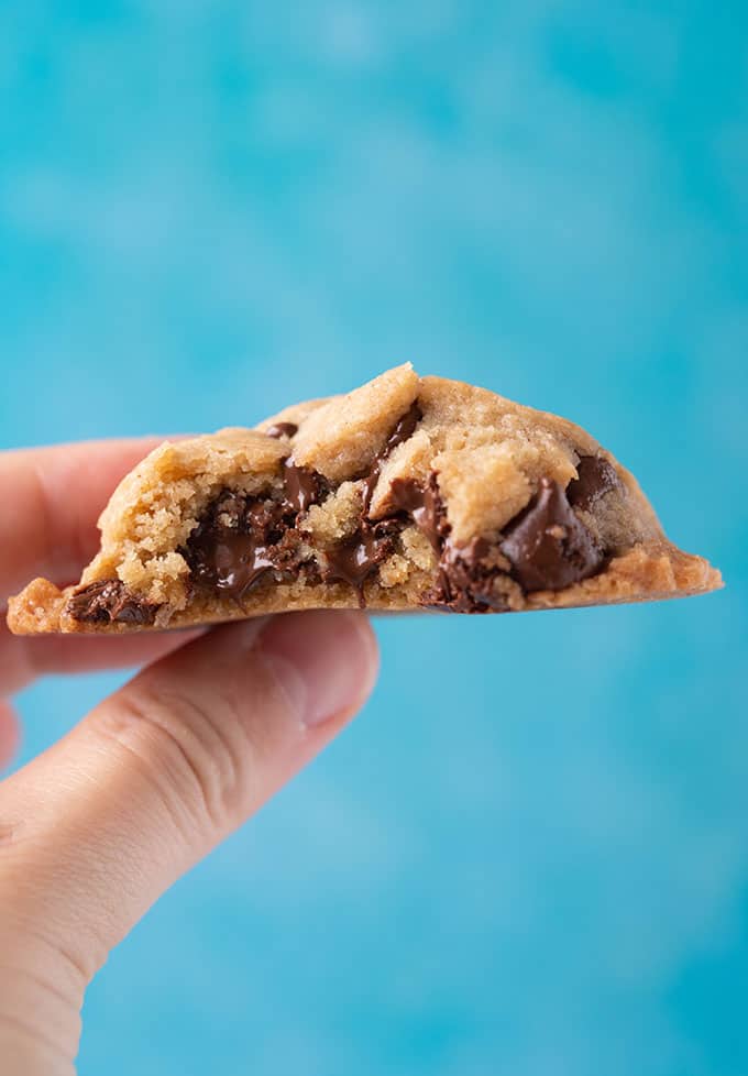 A hand holding a gooey Vegan Chocolate Chip Cookie