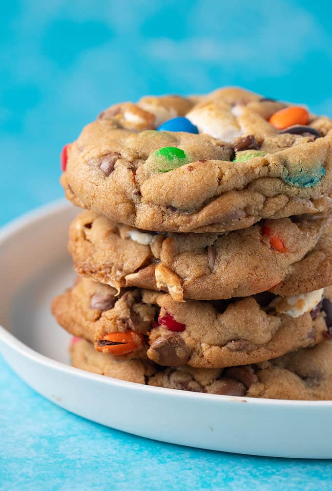 A stack of thick and chewy M&M Cookies on a white plate