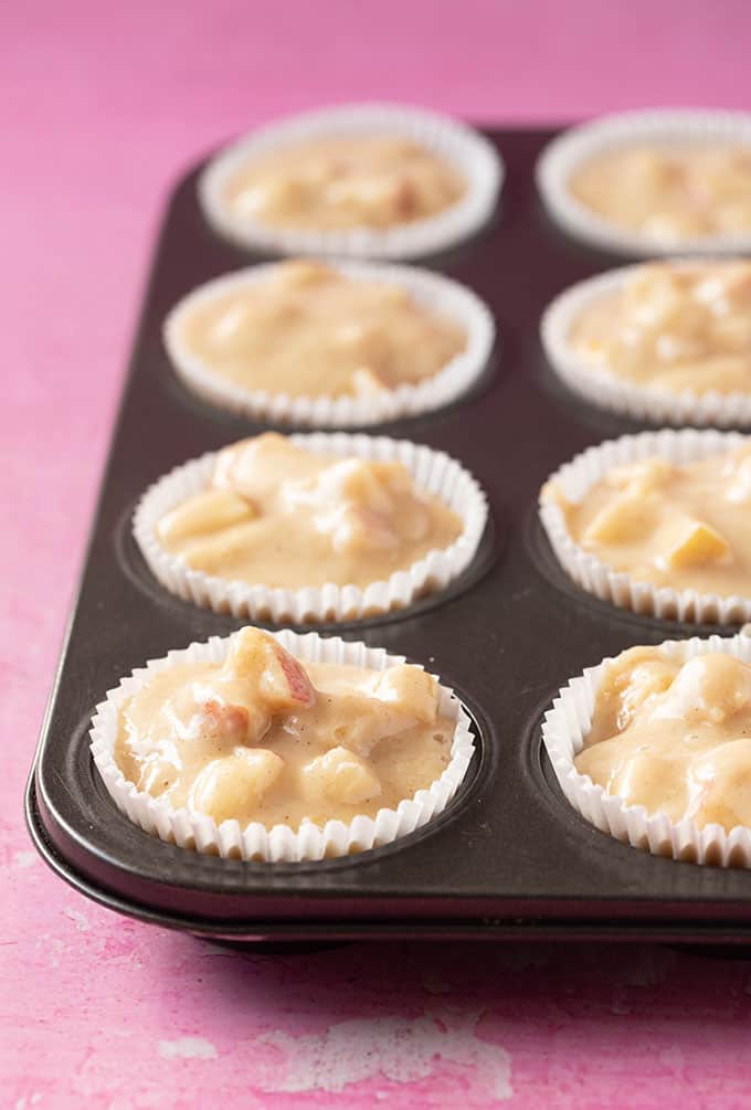 A muffin tin filled with Apple Muffin batter ready for the oven