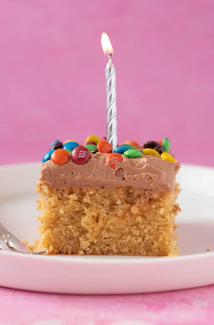 A piece of Peanut Butter Sheet Cake with a candle in it