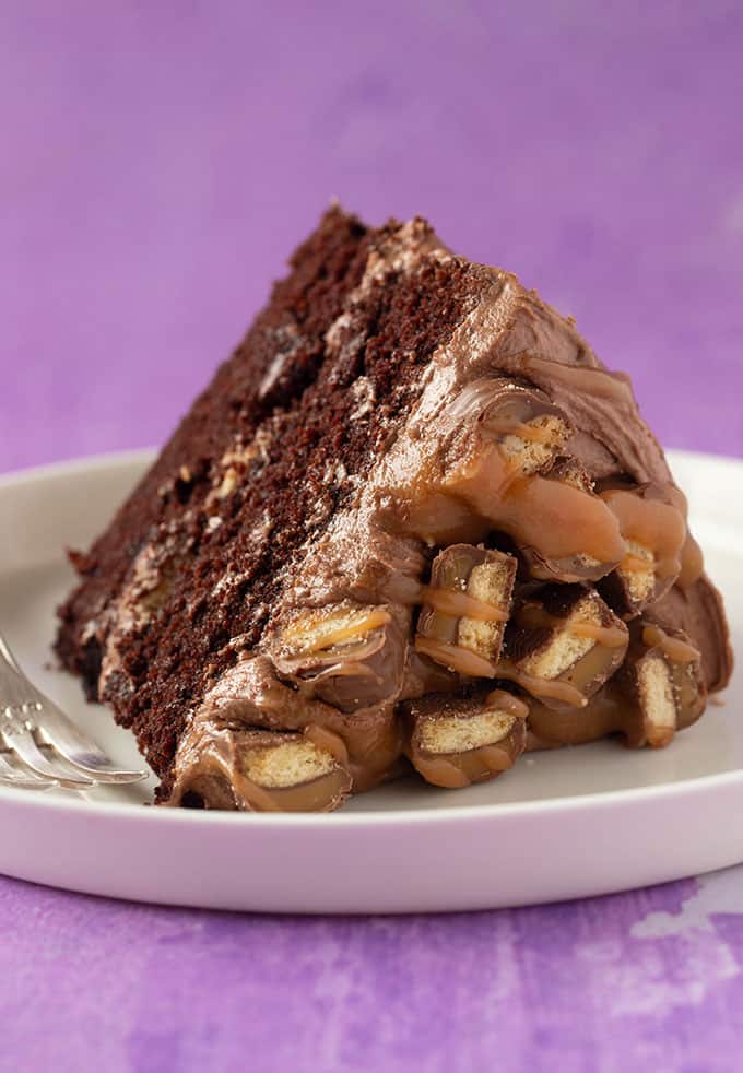 A big slice of chocolate cake covered in Twix Bars