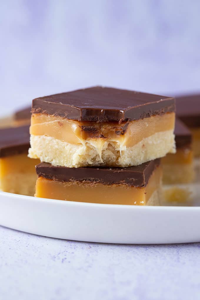 A stack of homemade Caramel Squares on a purple background