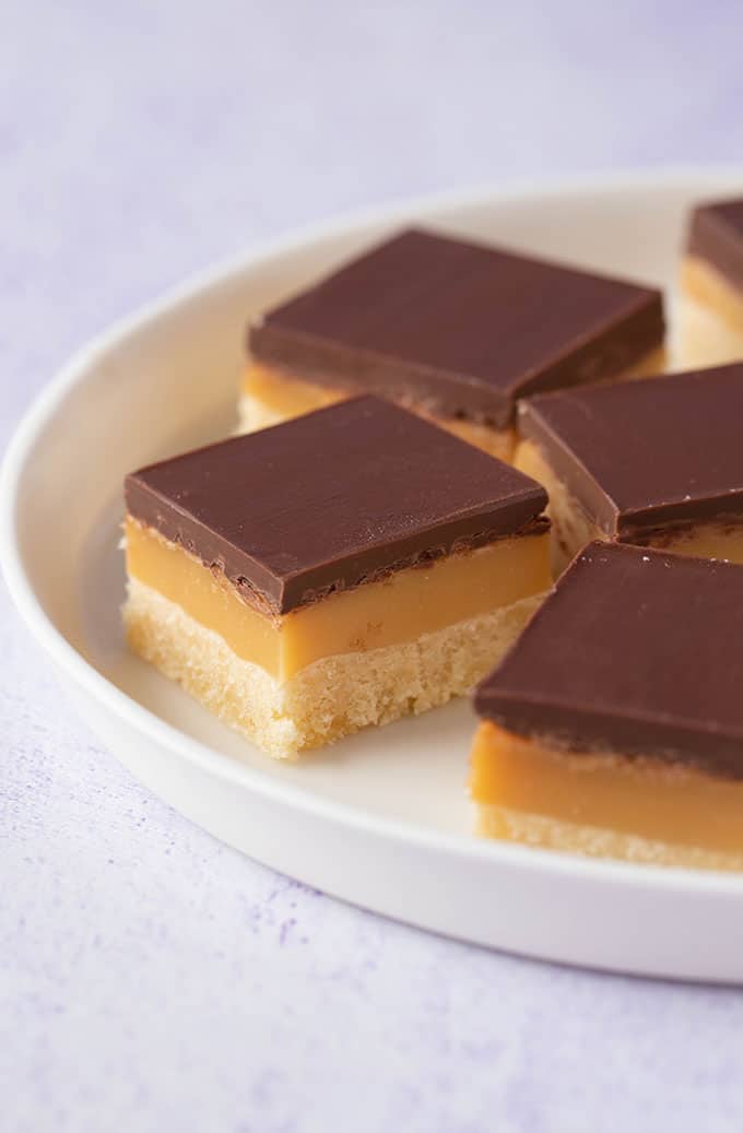 A white plate filled with pieces of homemade Caramel Slice 